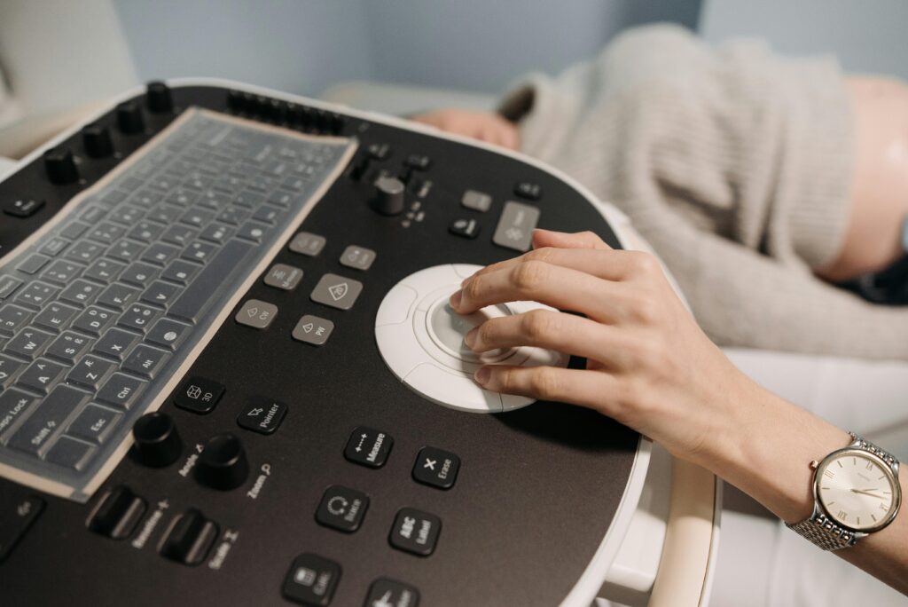 A hand operates medical ultrasound equipment, focusing on healthcare technology.